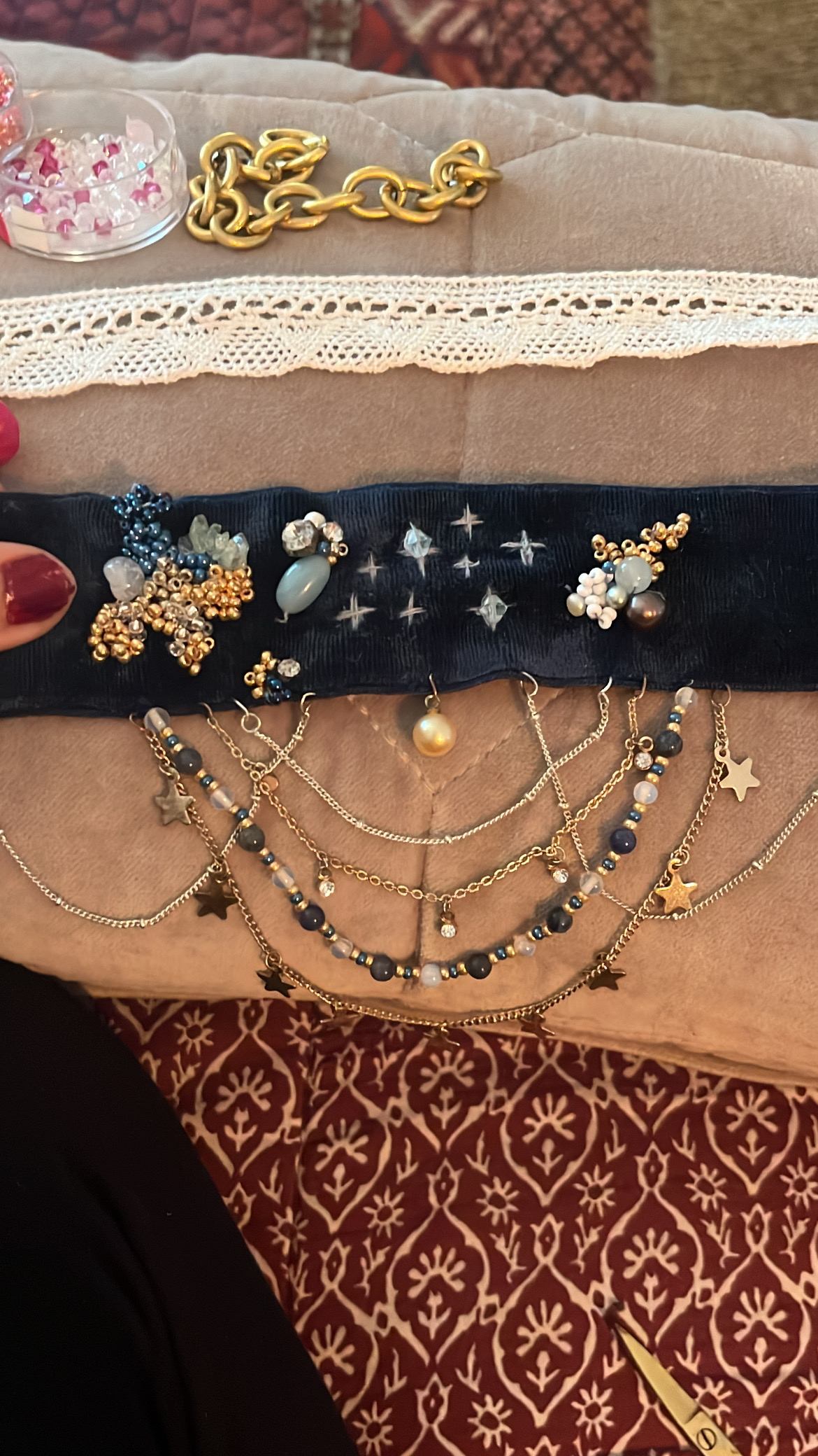 A choker in progress, beads laid out on velvet ribbon
